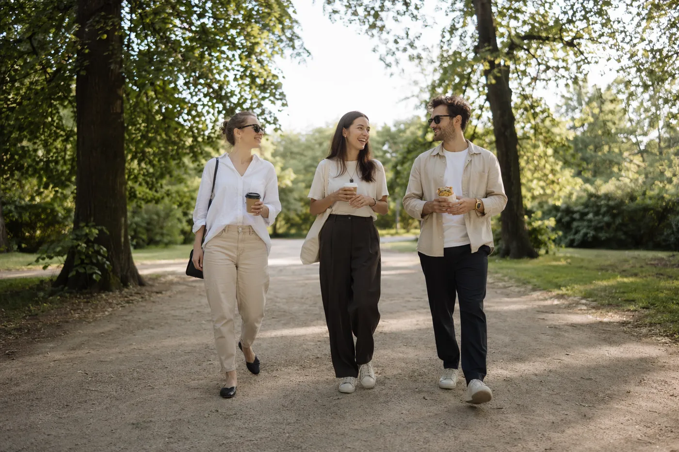 Three people meeting for the first time, walking and chatting through a green Warsaw park